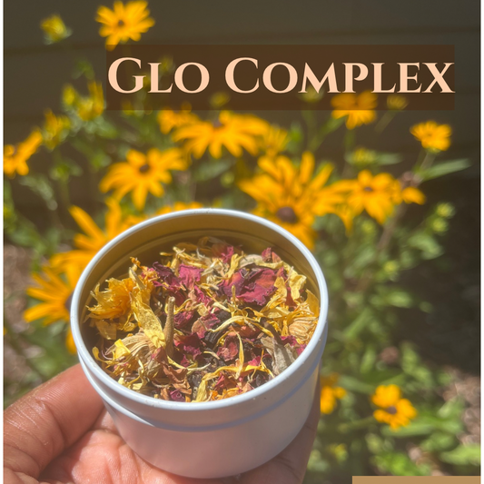 Hand holding a white container with dried flowers against a background of yellow flowers and 'GLO COMPLEX' text.