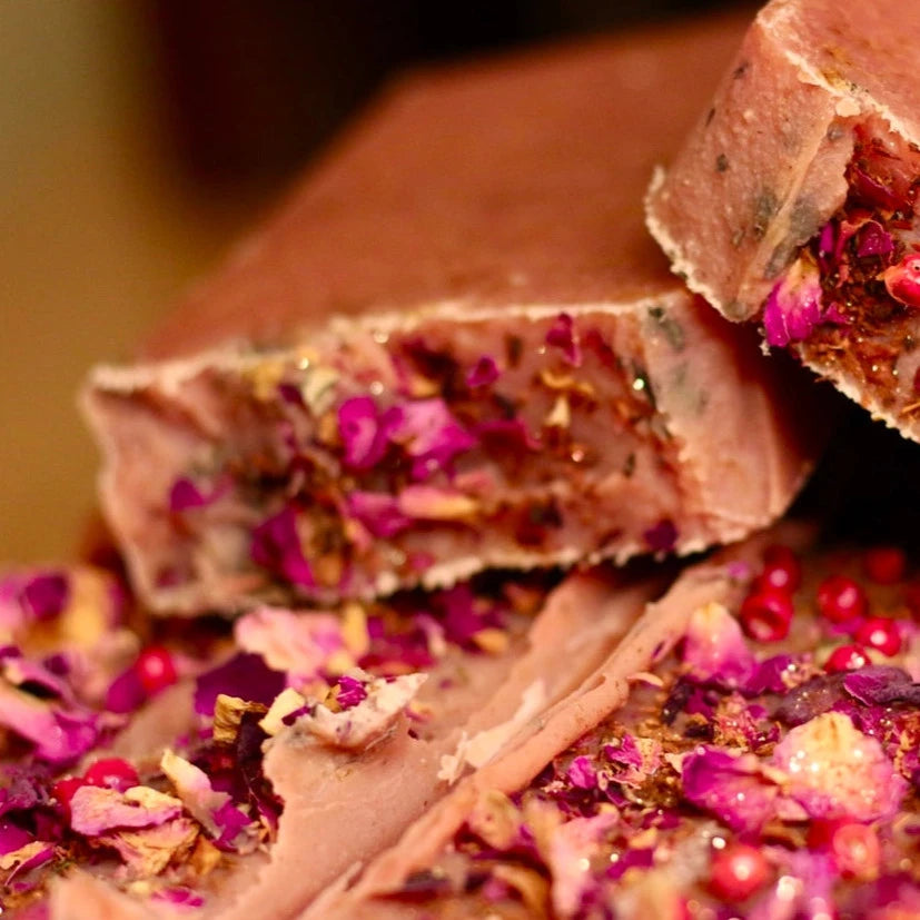 A bar of soap with visible floral petals embedded in its surface, indicating a luxurious and artisanal craft.