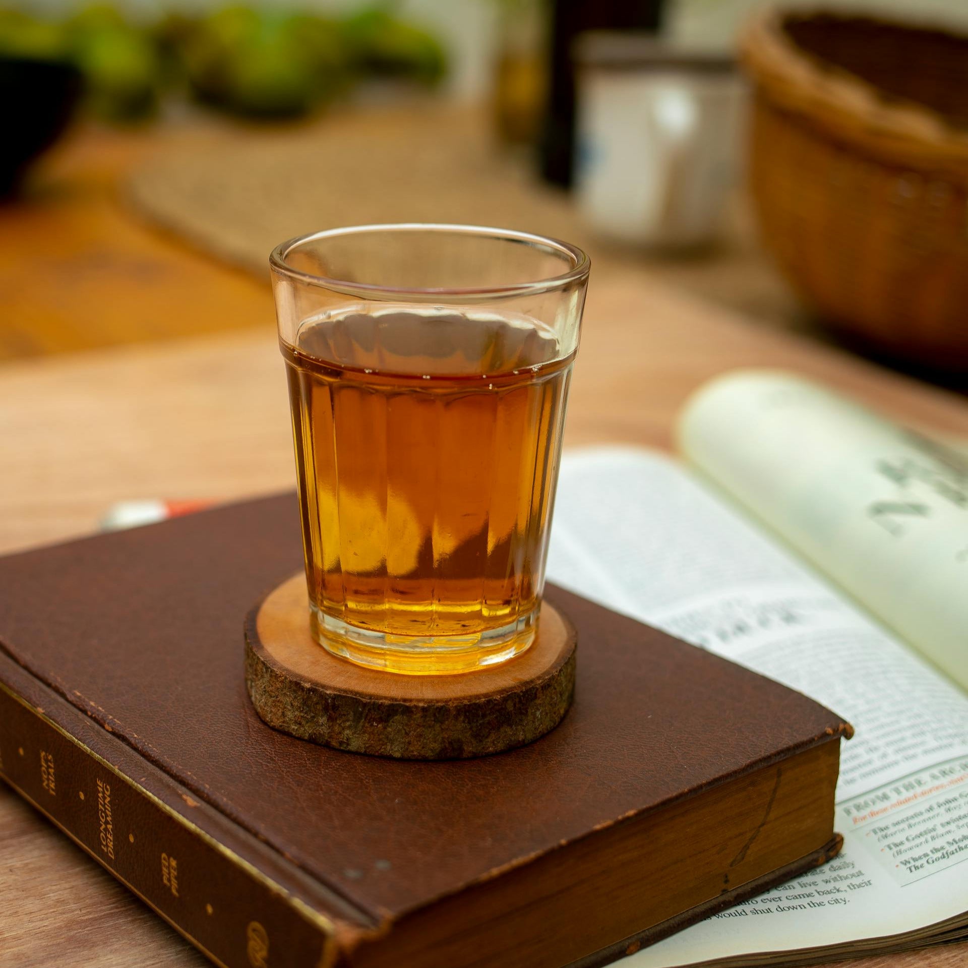 Glass of tea on a cork coaster over an open book with a blurred background