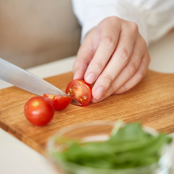 Someone cutting up a tomato, representing the cooking class offered by Charly as one of the raffle items