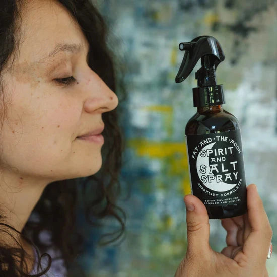 Person holding a bottle labeled 'Spirit and Salt Spray' against a blurred background