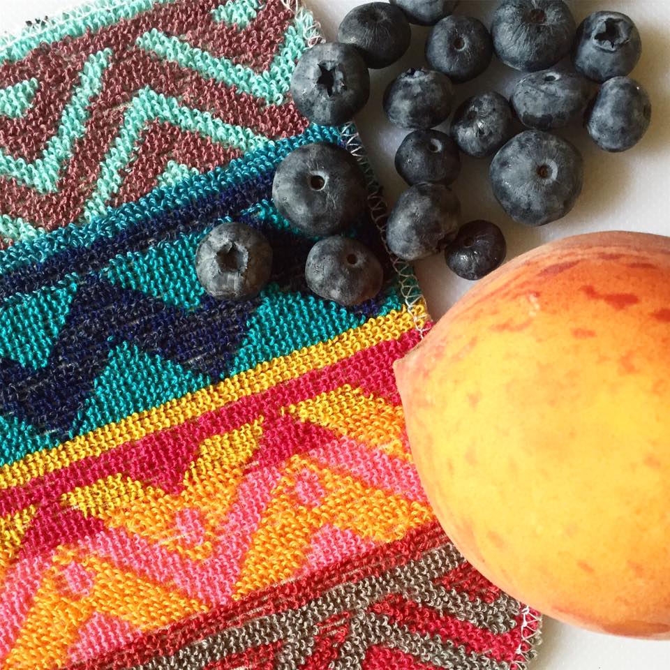 A colorful EuroScrubby next to a peach and a cluster of blueberries.
