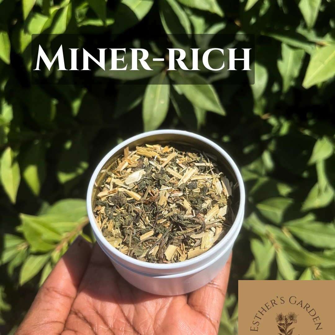 Hand holding a container of dried herbs with 'Miner-Rich' text and 'Esther's Garden' branding against a green leafy background.