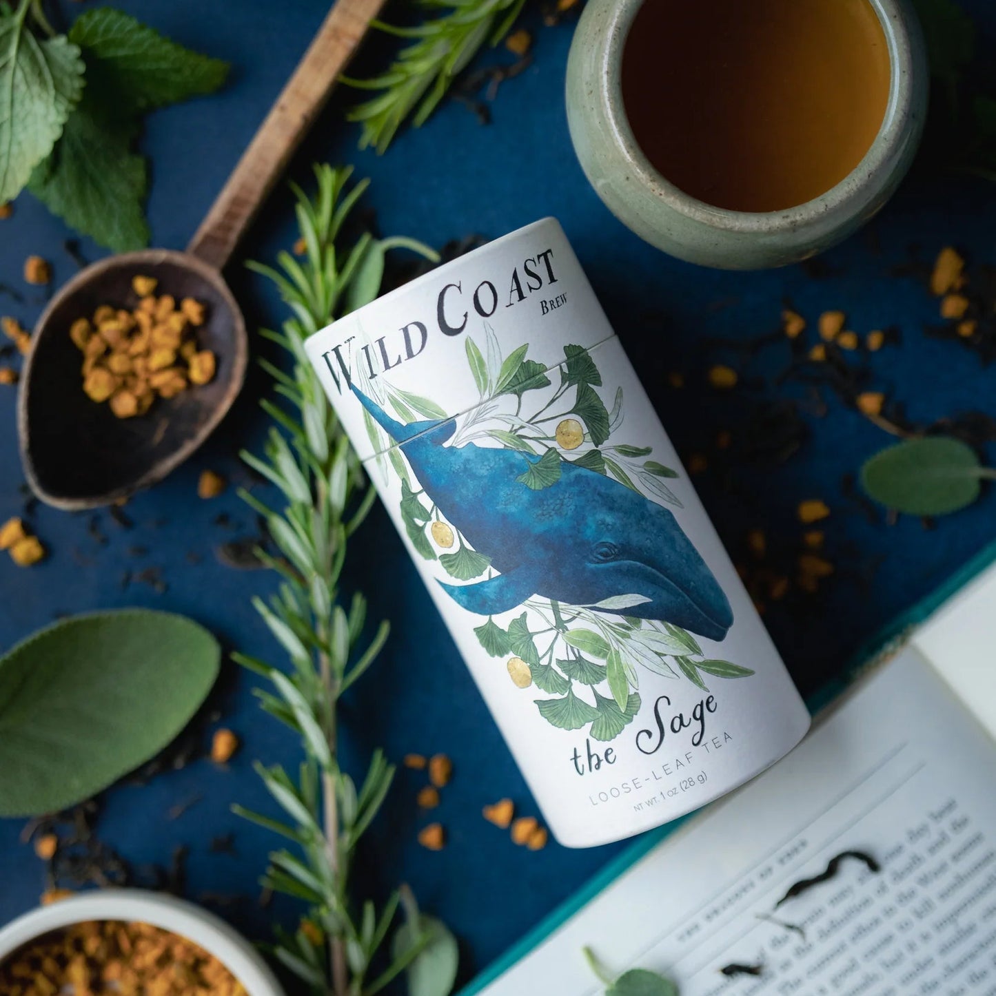 Wild Coast tea canister with herbs and a book on a blue background