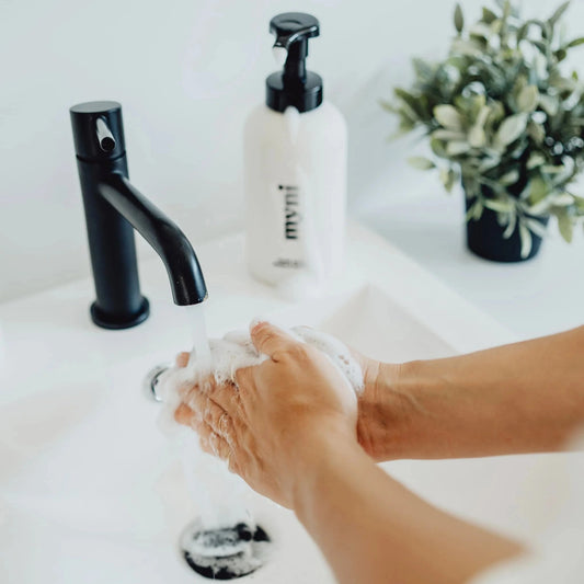 Person washing hands with foaming hand soap tablets in zero waste bathroom.