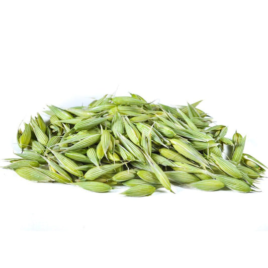 A pile of fresh green oat tops with visible pale grains, photographed on a plain white background.