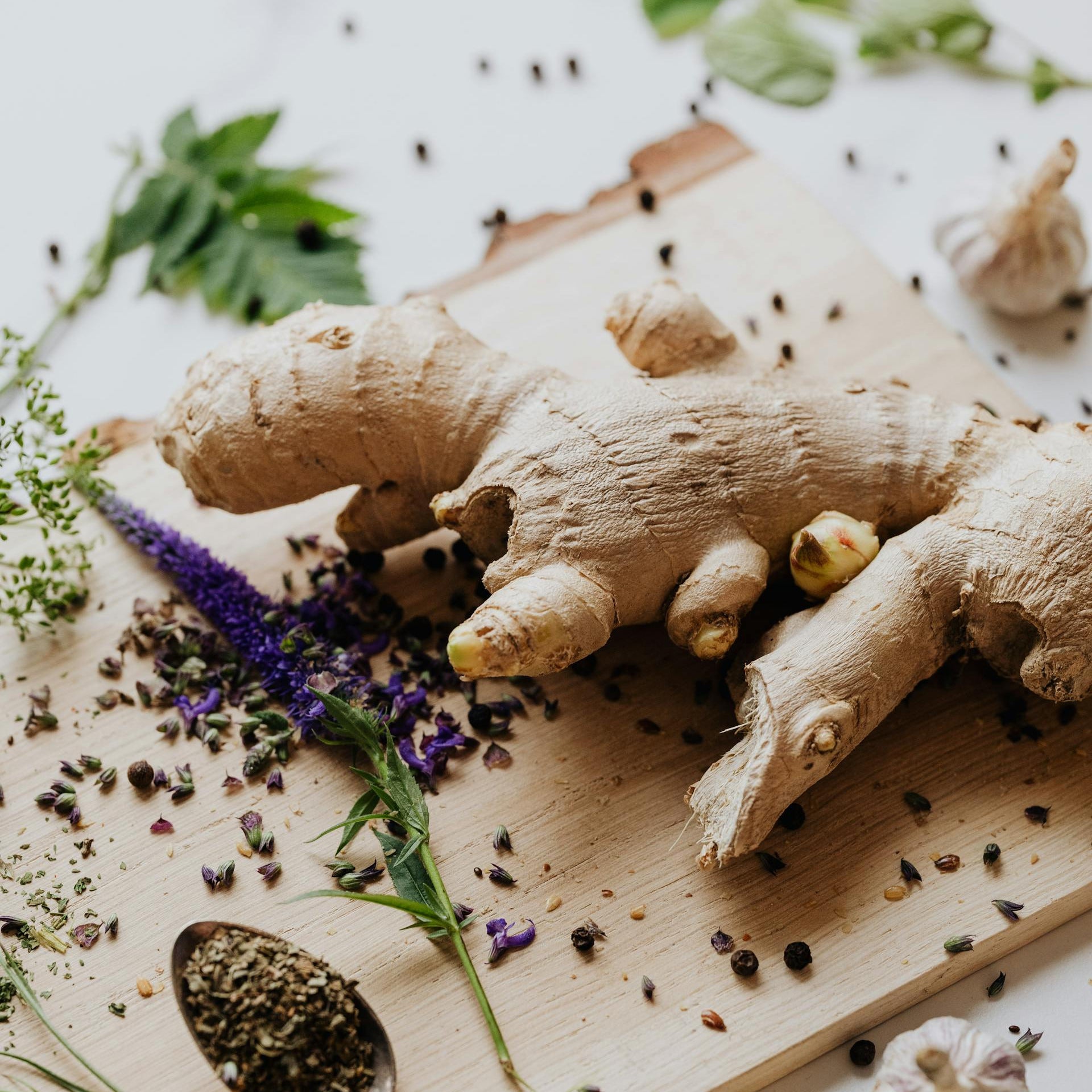Ginger root on a wooden board with herbs and spices