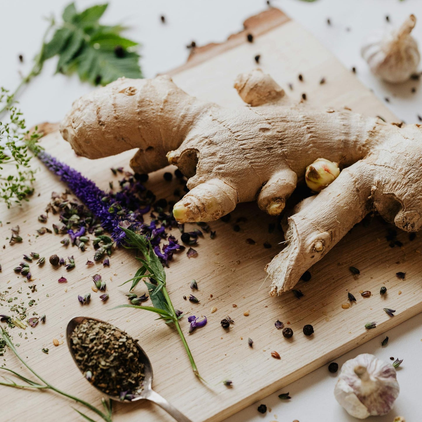 Ginger root on a wooden board with herbs and spices