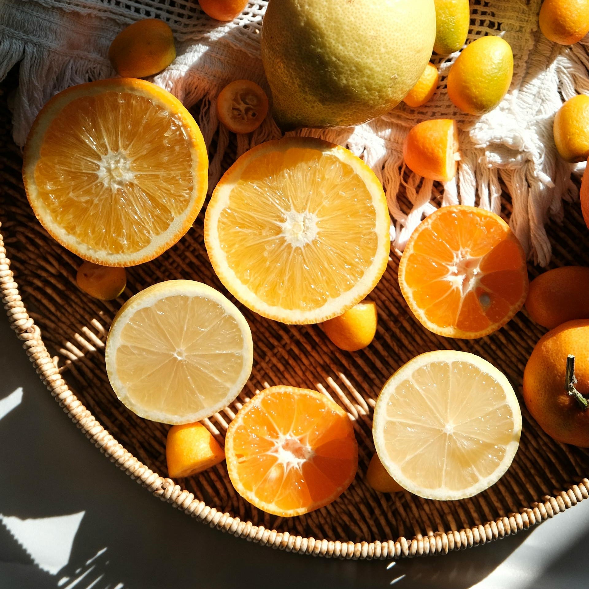 Assorted citrus fruits including oranges and lemons on a woven surface.