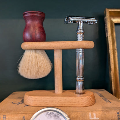 Shaving brush, razor, and other grooming items on a dark surface with a green background